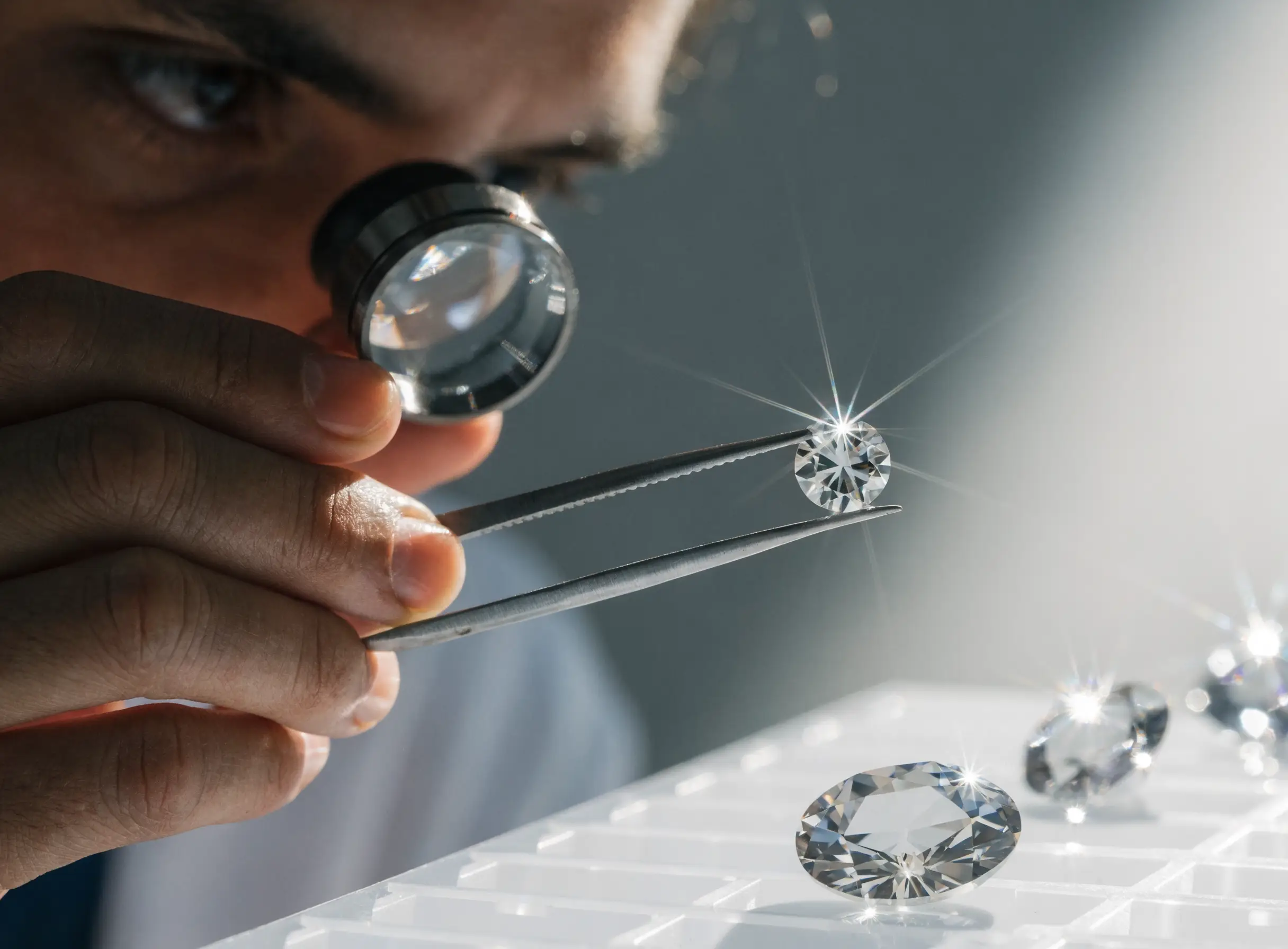 A gemologist examining a diamond with a loupe and tweezers