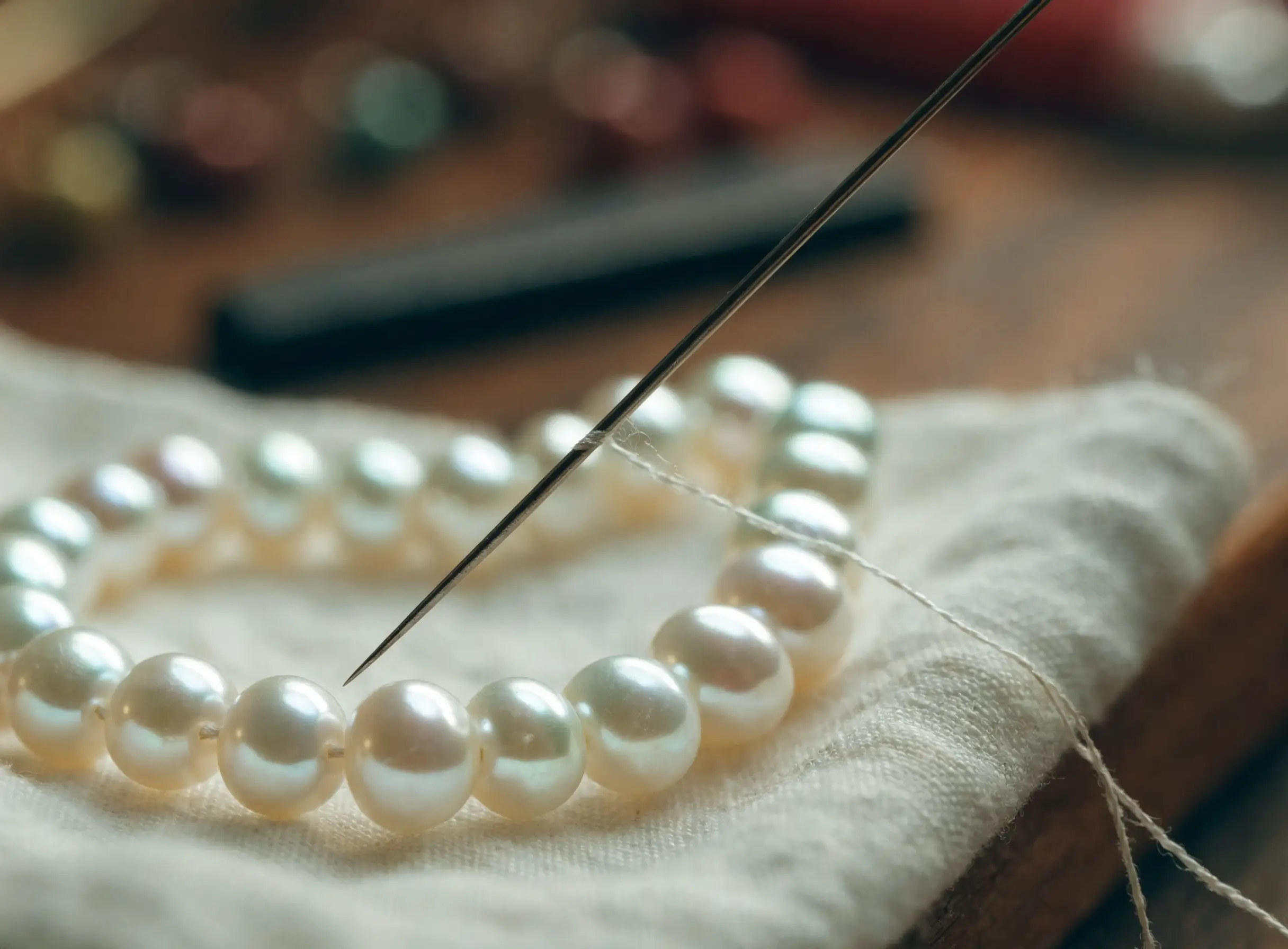 A strand of pearls being restrung on a jeweler’s bench